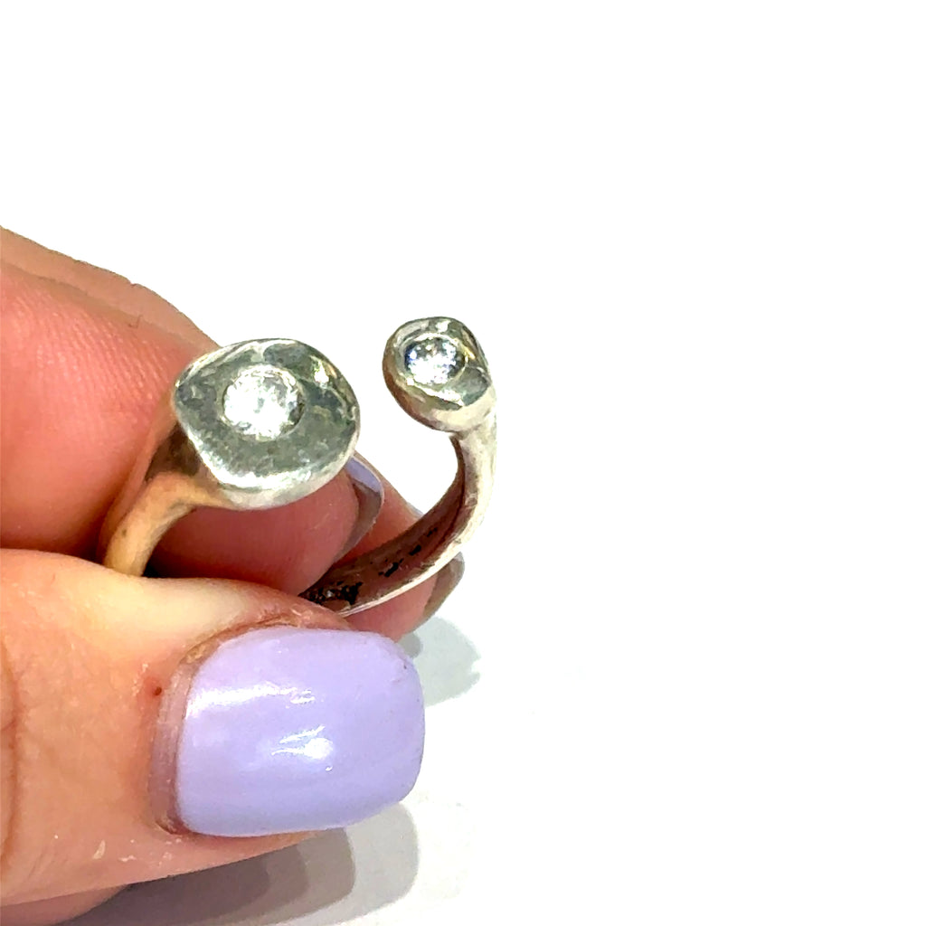 Handcrafted sterling silver bubble ring with clear CZ accents — open shank design in a models finger tips to show a close up view on a white background.
