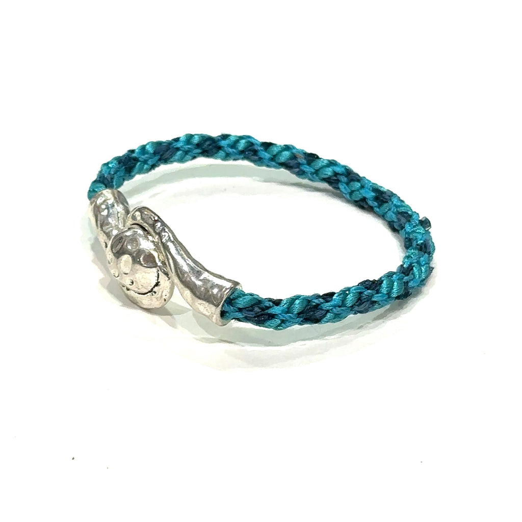 Handmade Kumihimo braided bracelet with silver clasp, featuring ribbon and satin cord deep blue on white slight left angle view