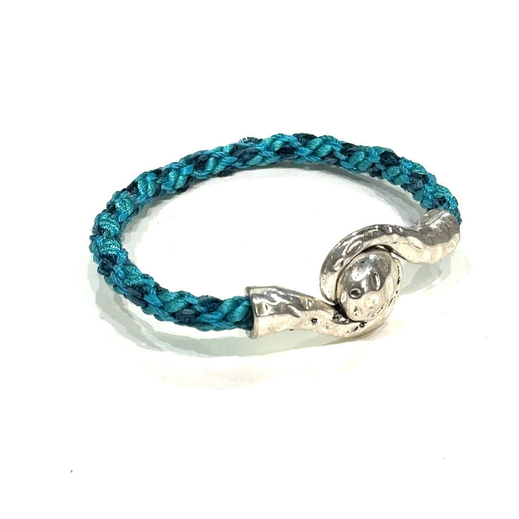 Handmade Kumihimo braided bracelet with silver clasp, featuring ribbon and satin cord deep blue on white slight right angle view