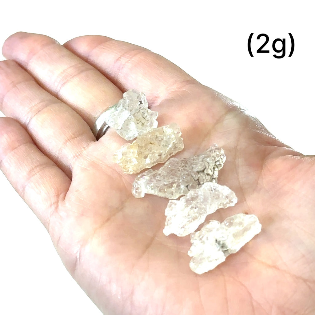 Healing Hyalite Opal crystal for intuition, serenity, and inner peace grouping of (2g) on white in hand for overview