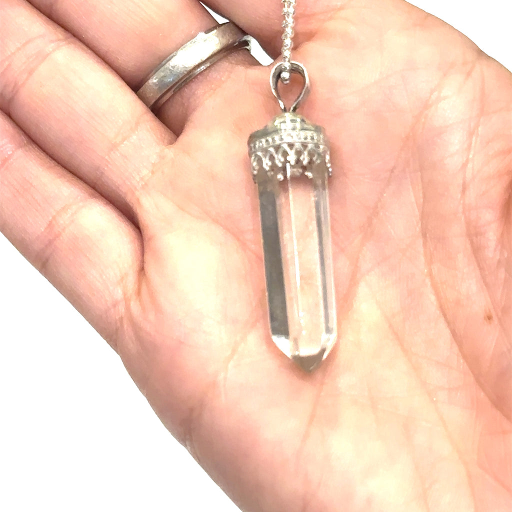 "Healing crystal jewelry – Clear Quartz pendant on 18 inch silver chain" on white in hand for a close up view
