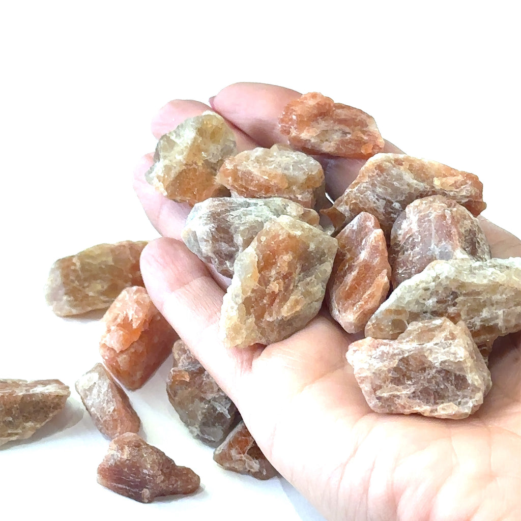 Healing sunstone crystal for vitality, creativity, and aura cleansing grouping in hand on white overview