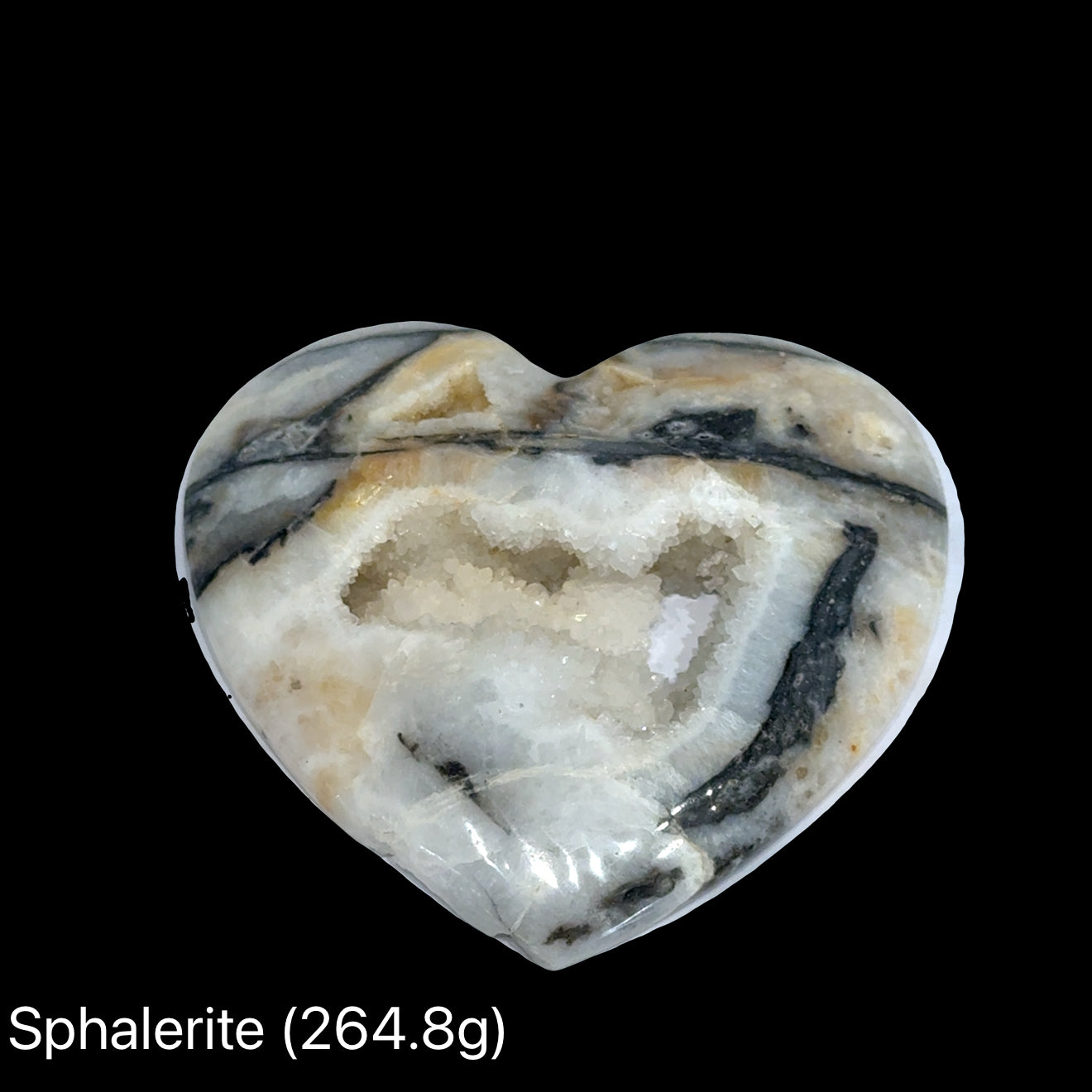 Heart-shaped sphalerite crystal on a black background with weight indication #B (264.8), front view.