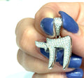 Hebrew Chai life symbol pendant in polished sterling silver with paved CZ detail on a white background, in a models hand, front overview. 