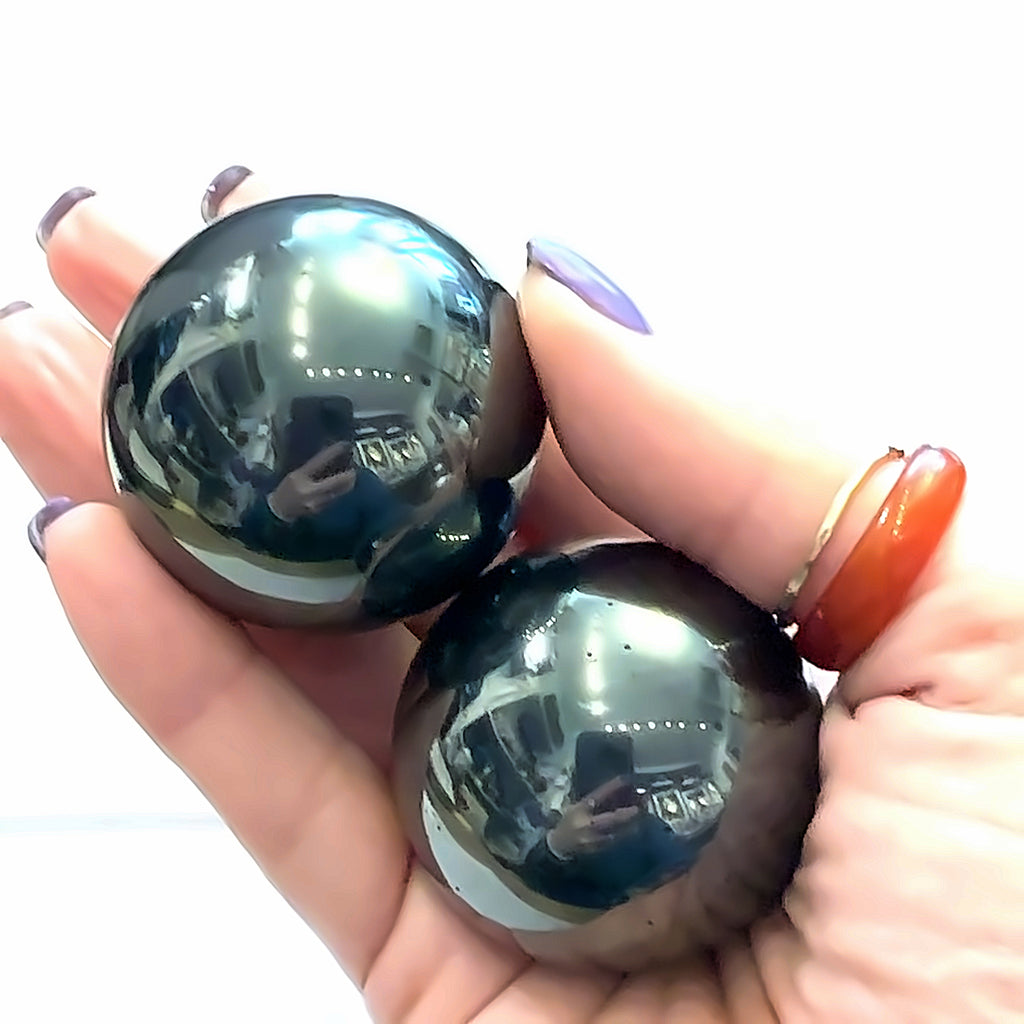 Hematite Sphere Gemstone grouping in hand on white front overview