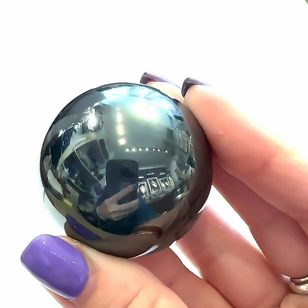 Hematite Sphere Gemstone in hand on white front overview