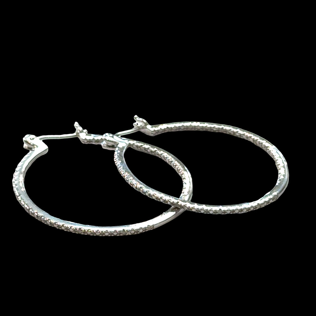 Inside-out diamond hoop earrings in sterling silver with snap-back closure showing sparkle, on a black background a close up front view. 