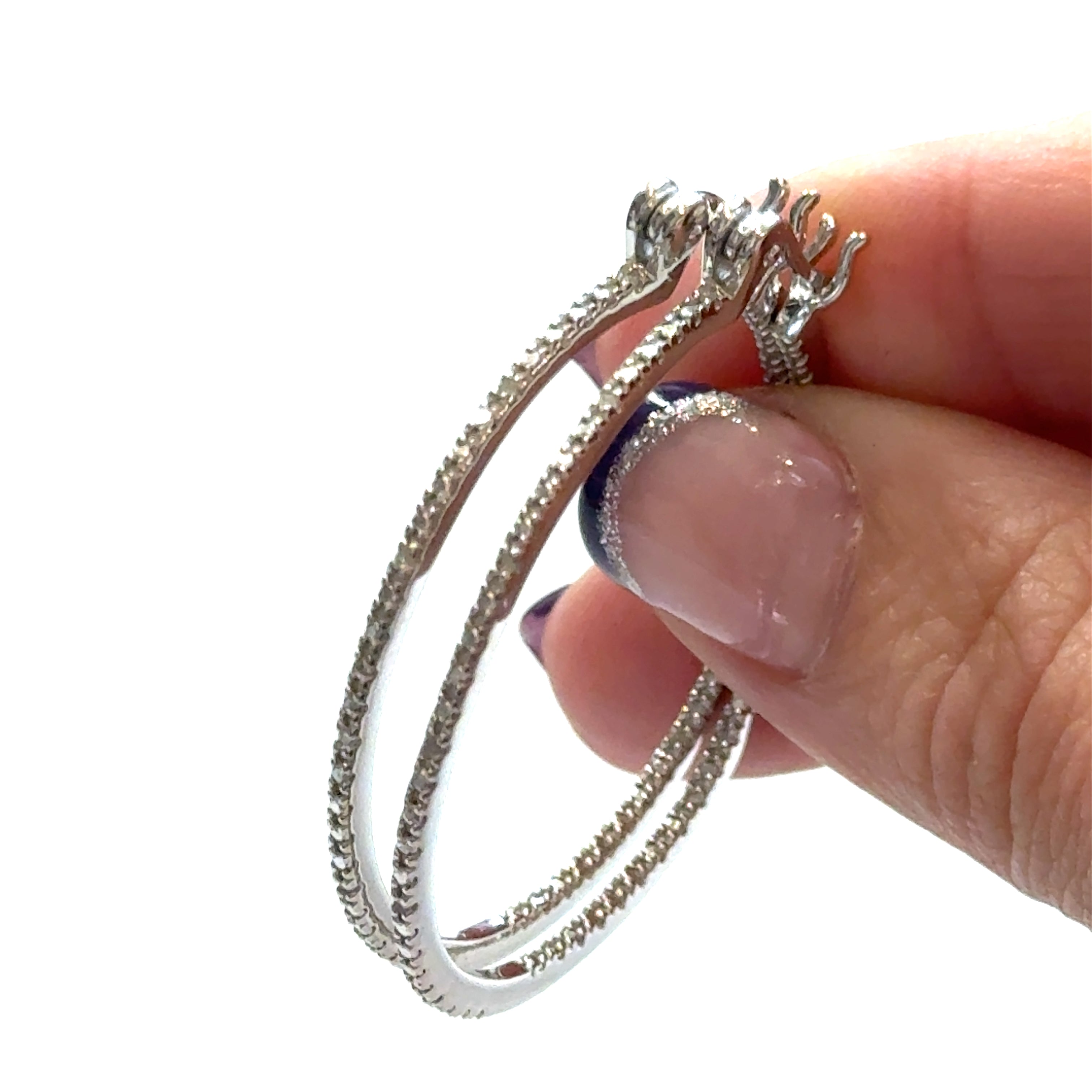 Inside-out diamond hoop earrings in sterling silver with snap-back closure showing sparkle, on a white background with a model holding for a close up front view. 