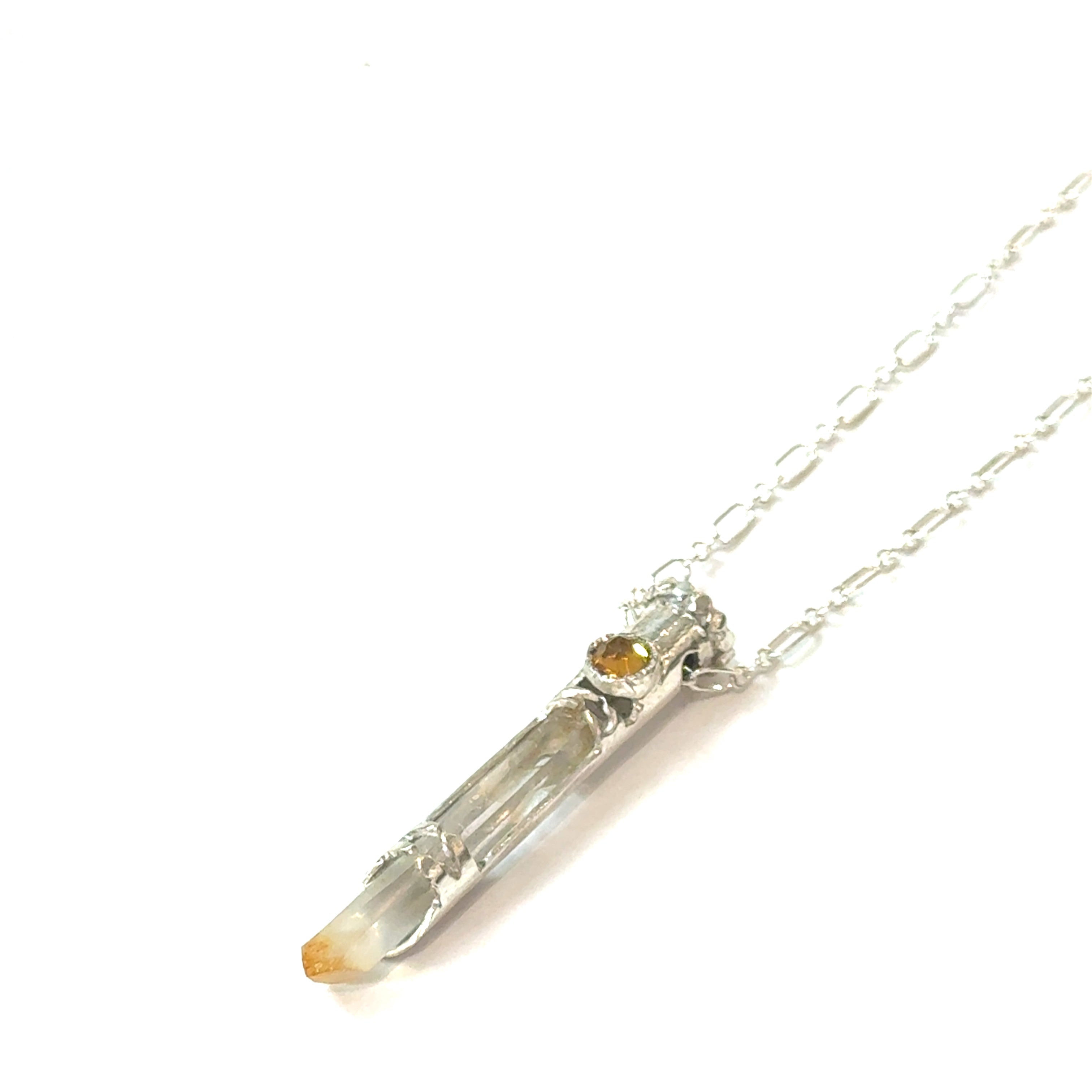 Mango Quartz Lightsaber Necklace in a Sterling Silver case with citrine gemstones to accent the pendant on a white background, in a models finger tips, front right angle hanging view. 
