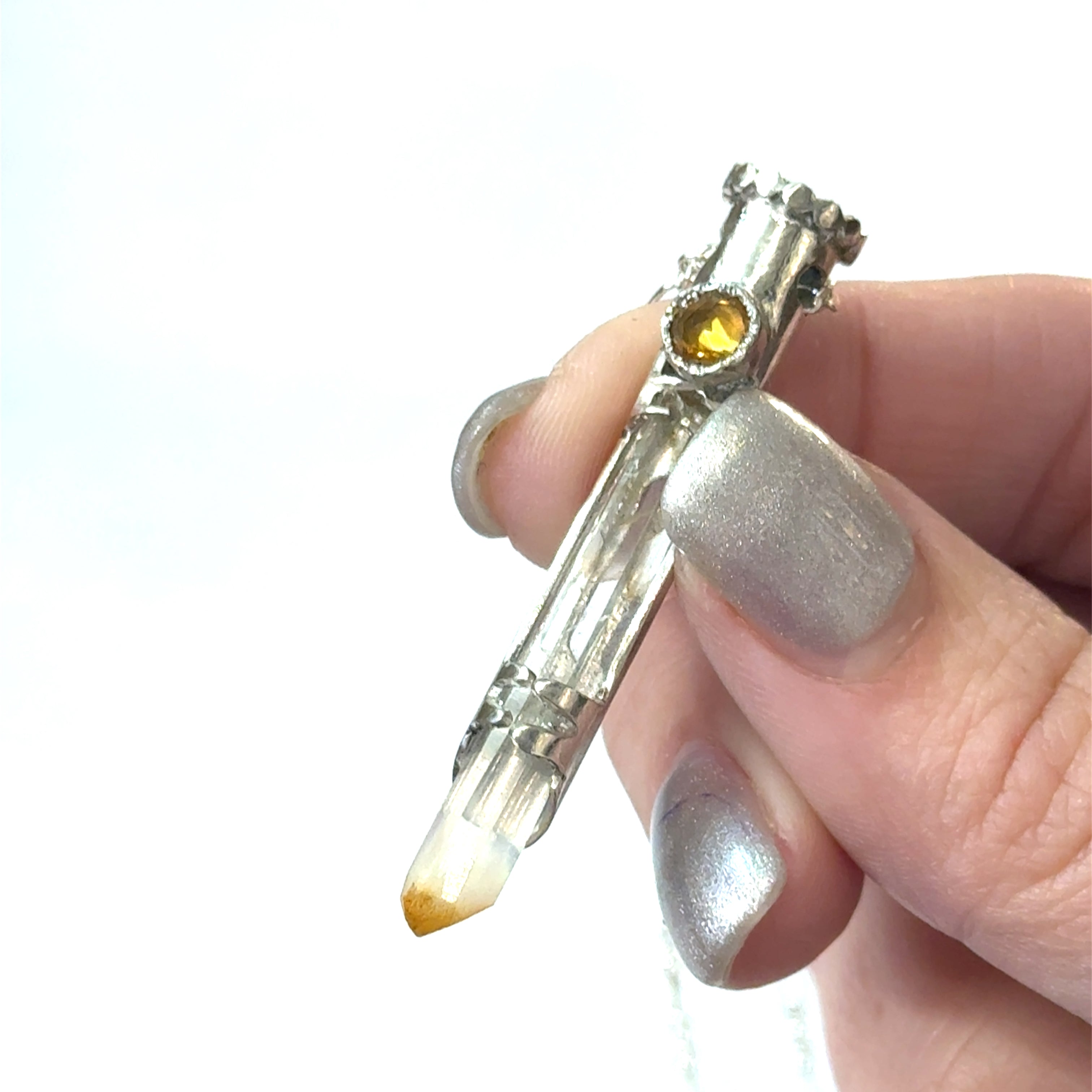 Mango Quartz Lightsaber Necklace in a Sterling Silver case with citrine gemstones to accent the pendant on a white background, in a models finger tips, front view. 