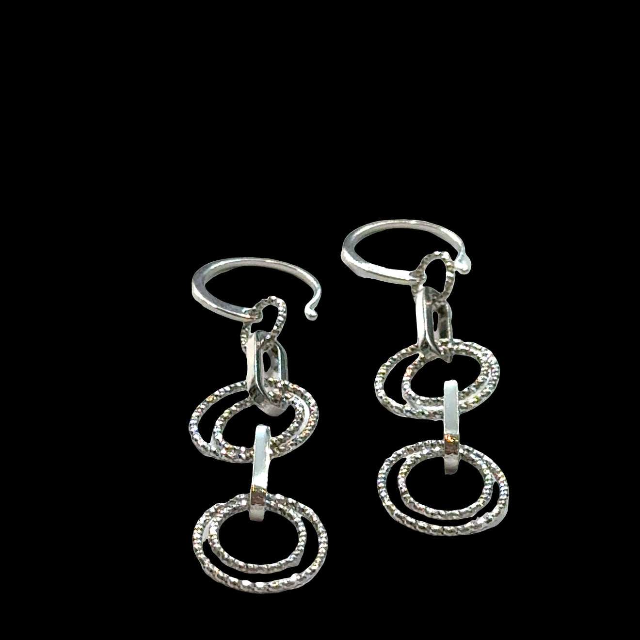 Multi-circle sterling silver dangle earrings with oval link showing sparkle and movement on a black background, front overview.