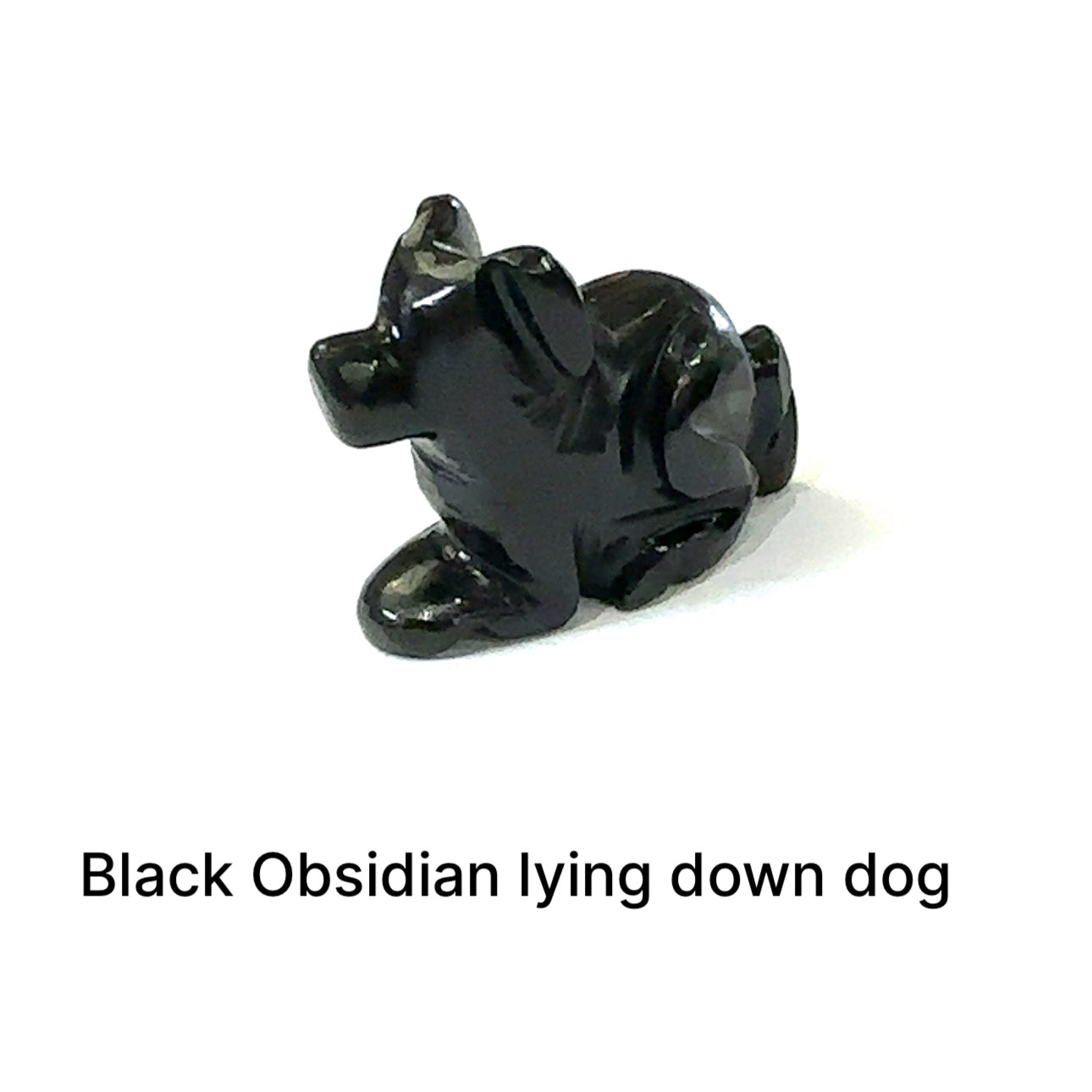 One Black Obsidian hound Dog gemstone carving lying down on white background, front view.