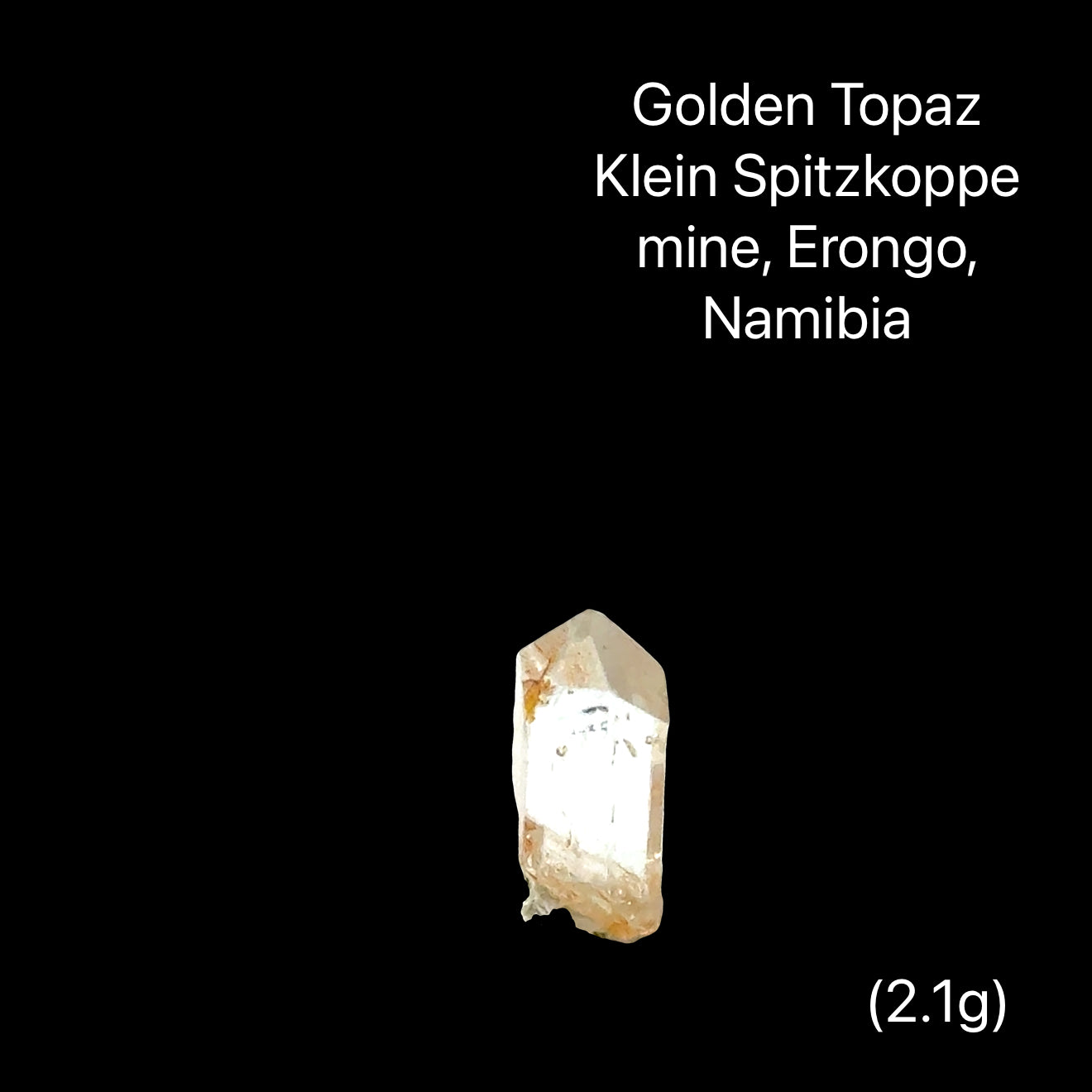 One rough golden topaz crystals on a black background with text indicating their origin (2,1g), front View.
