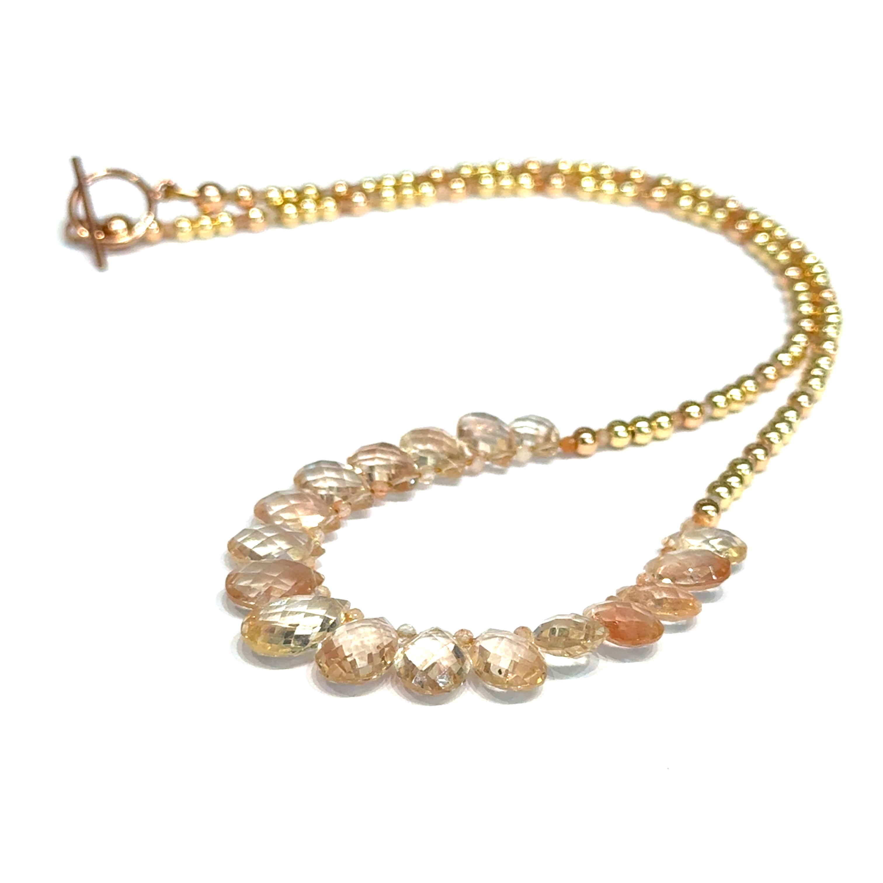 Oregon sunstone teardrop statement necklace with faceted focal stone and mixed metal sunstone beads showing peachy-copper brilliance on a white background, front view. 