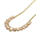 Oregon sunstone teardrop statement necklace with faceted focal stone and mixed metal sunstone beads showing peachy-copper brilliance on a white background, long left angle front view. 