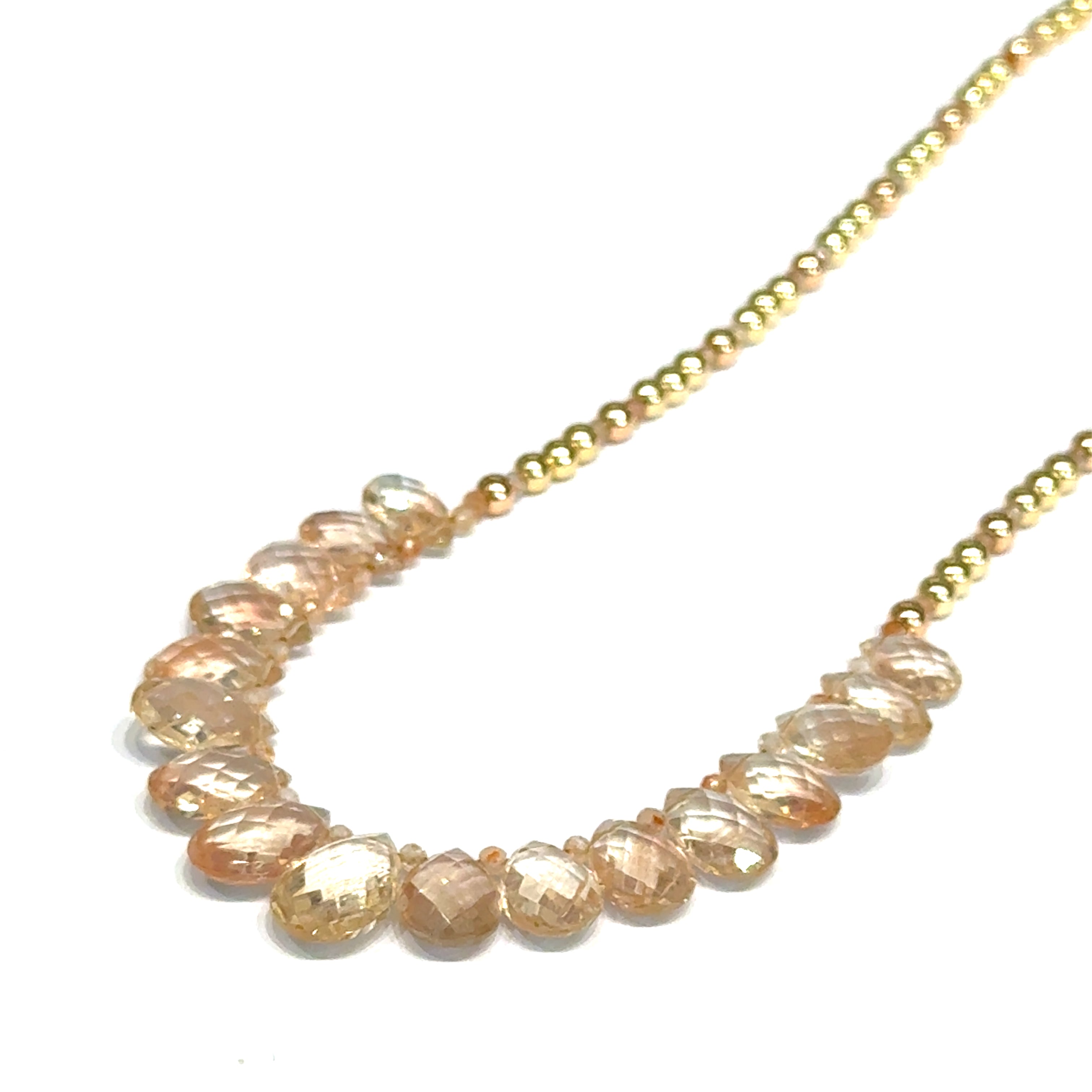 Oregon sunstone teardrop statement necklace with faceted focal stone and mixed metal sunstone beads showing peachy-copper brilliance on a white background, long left angle front view. 