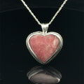 Pink Cobolto Calcite Heart-shaped gemstone pendant on a silver chain against a black background, front view. 