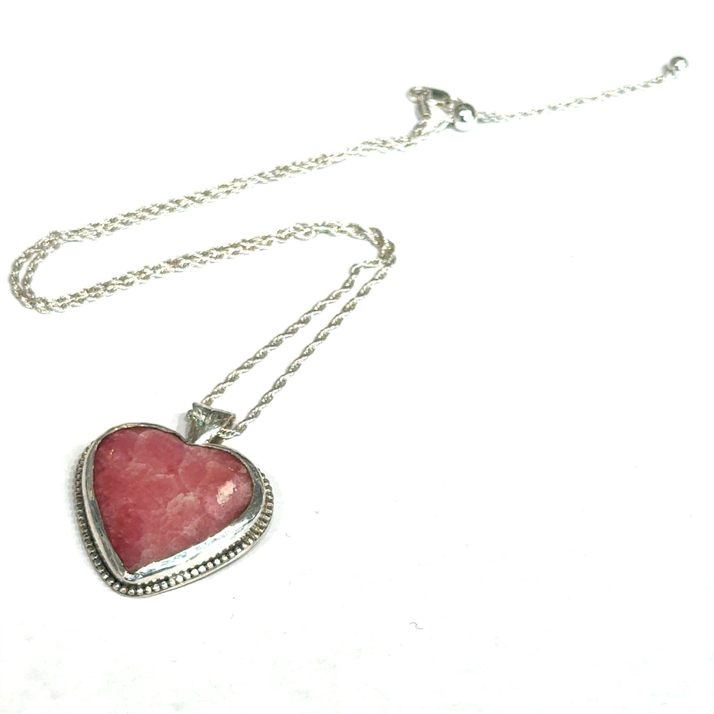 Pink Cobolto Calcite Heart-shaped gemstone pendant on a silver chain against a white background, front left angle overview. 