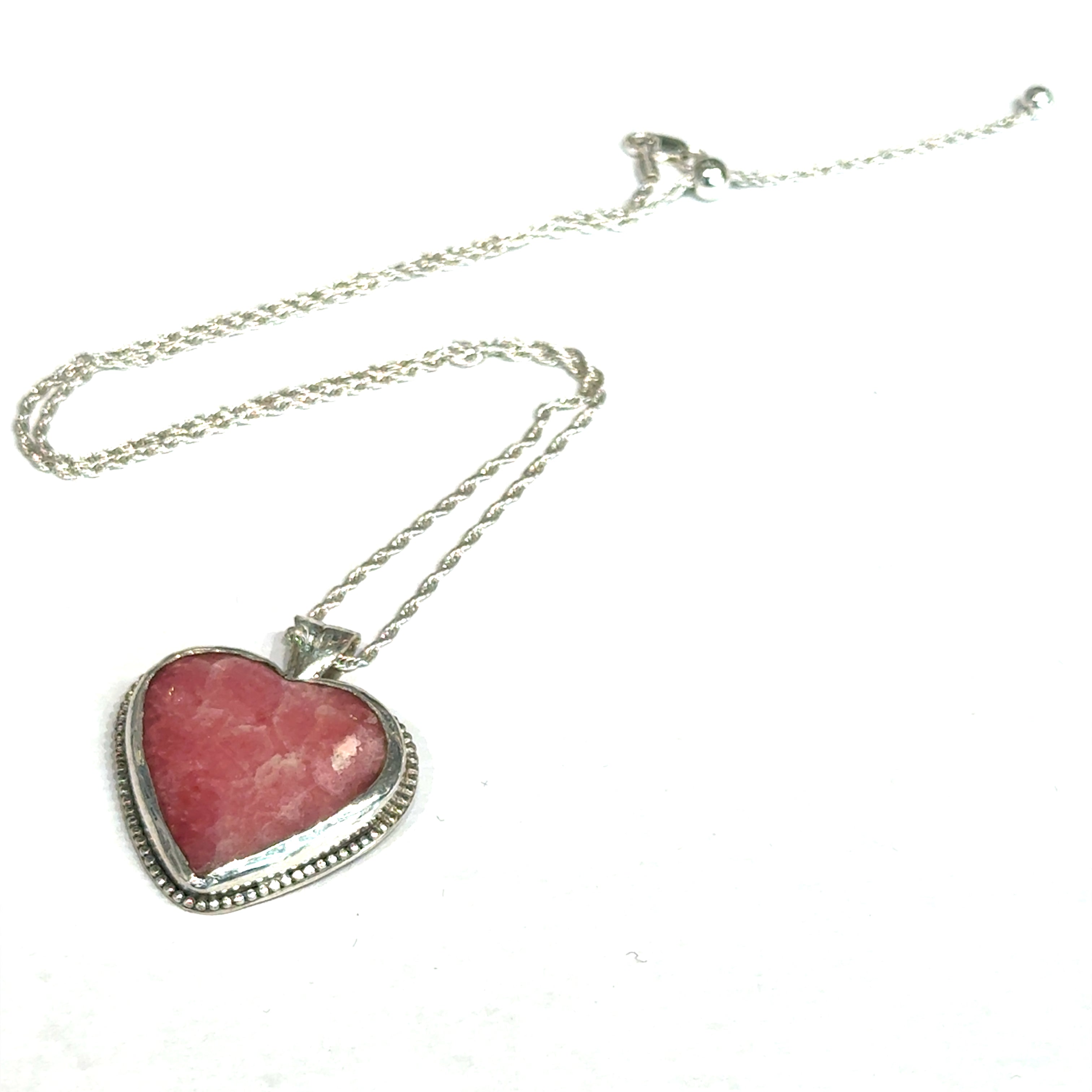 Pink Cobolto Calcite Heart-shaped gemstone pendant on a silver chain against a white background, front left angle overview. 