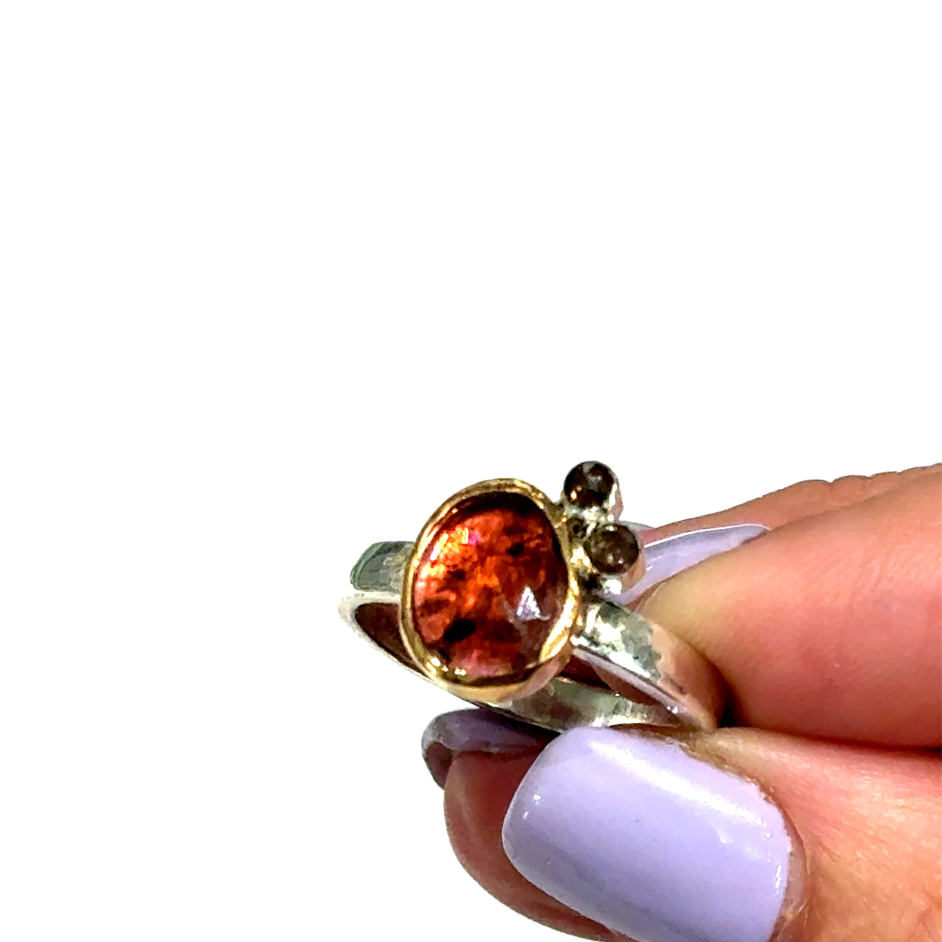 Pink sapphire and chocolate diamond mixed metal ring — handmade in Boston in a models finger tips and on a white background close up overview.