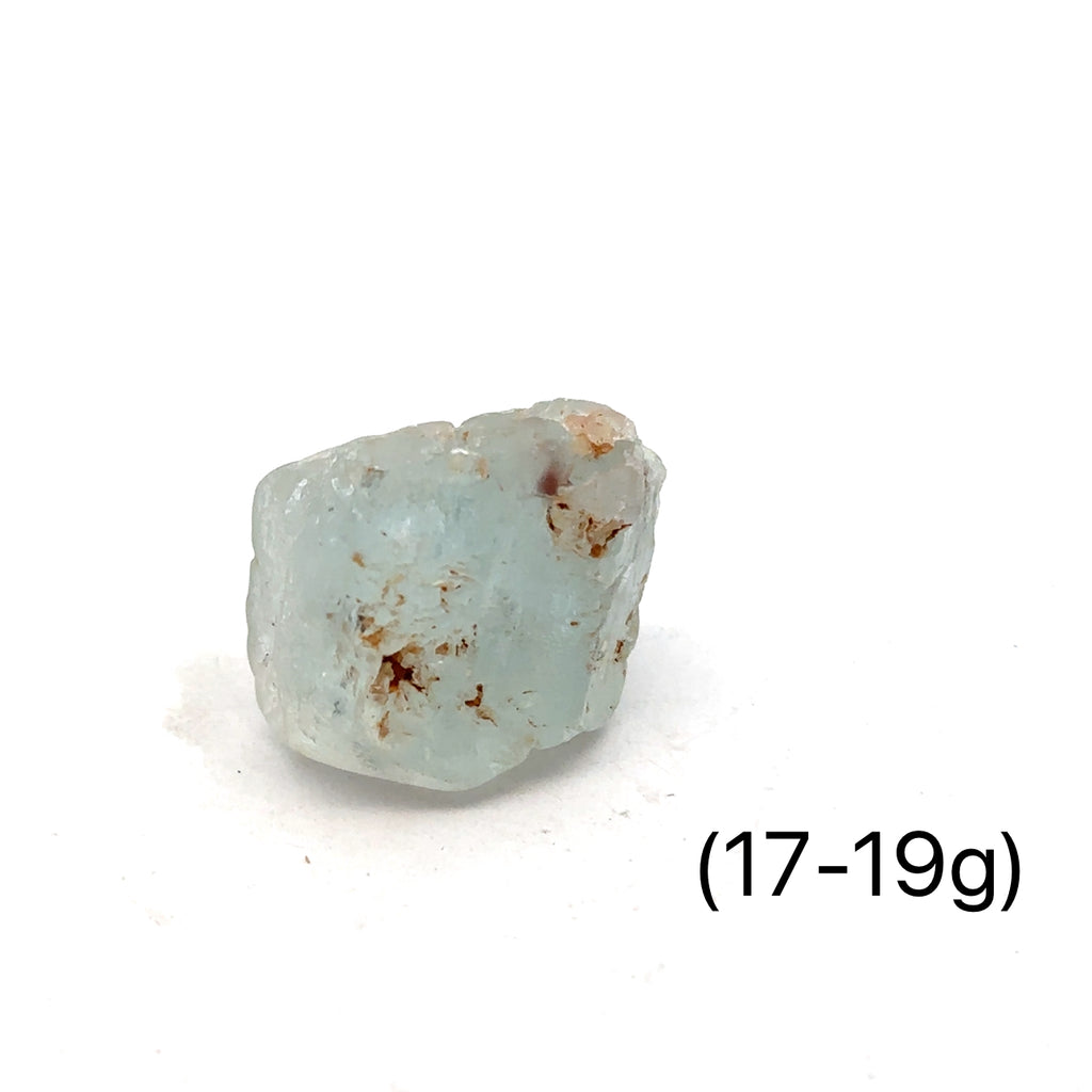 Raw Blue Topaz Gemstone on white grouping 17-19g front view 