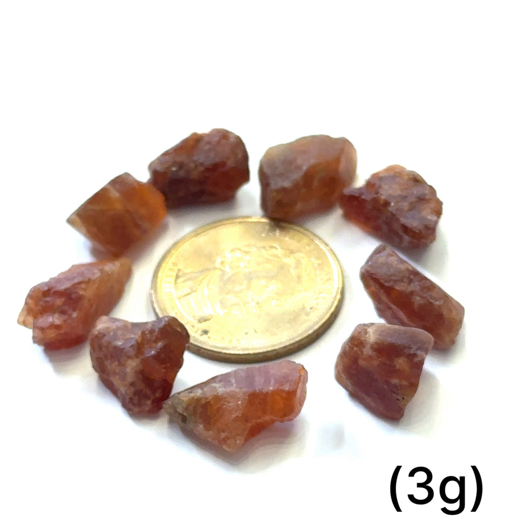 Raw Spessartine Garnet Gemstone grouping (3g) on white center 