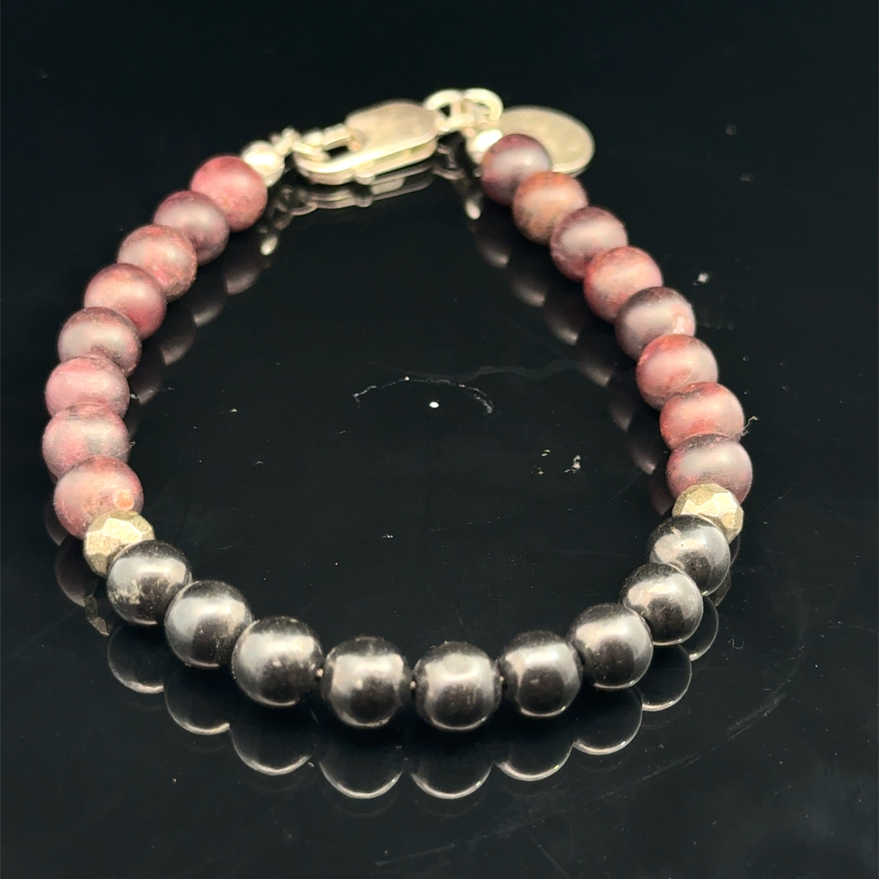 Red Garnet, Shungite, and Pyrite gemstone beaded bracelet with  a sterling silver lobster claw on a black background, front overview.