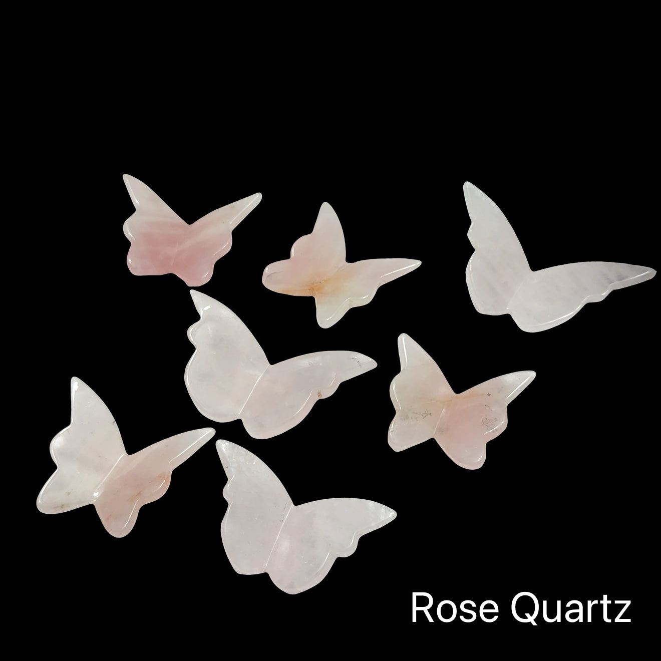 Rose Quartz butterfly-shaped crystals on a black background, front view. 