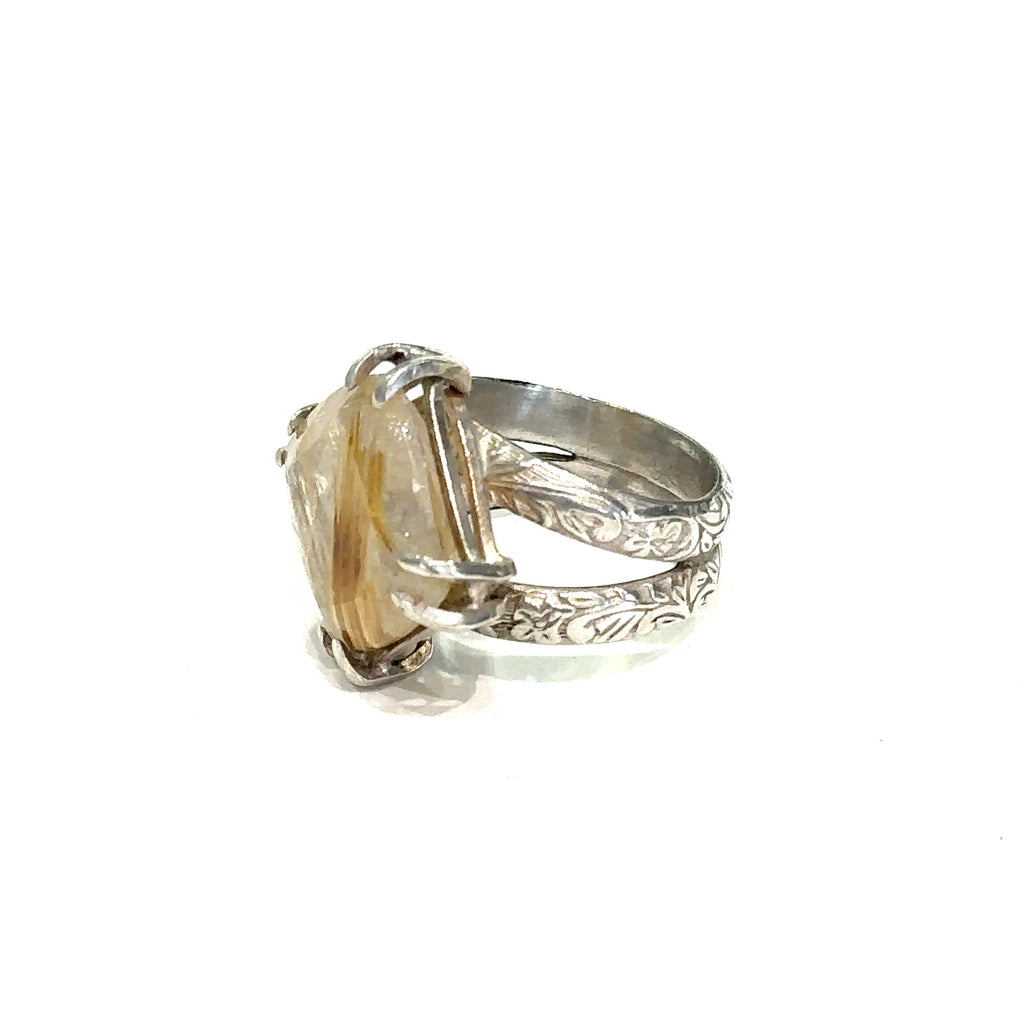Side view of split shank sterling silver band holding Golden Rutile gemstone left side view on white 