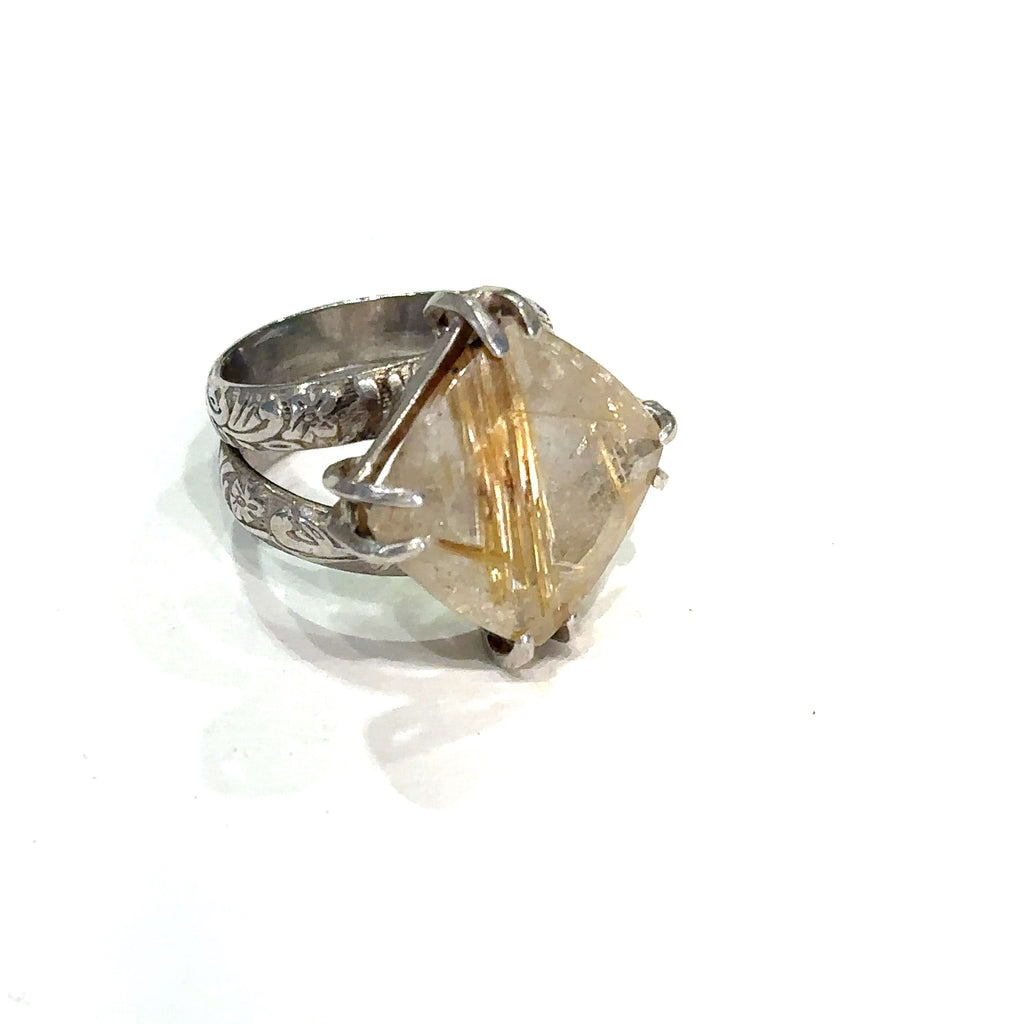 Side view of split shank sterling silver band holding Golden Rutile gemstone on white 
