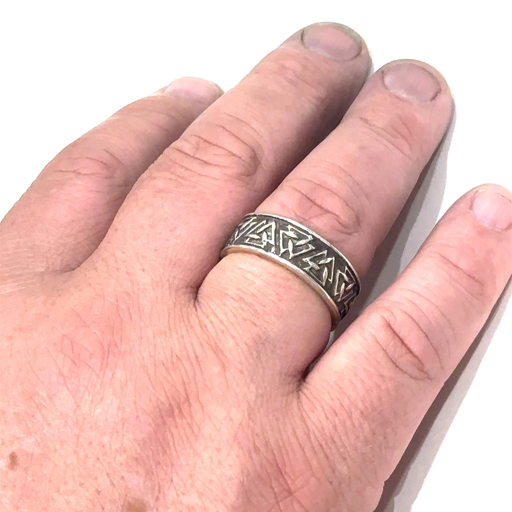 Statement men’s silver ring with geometric triangle symbolism on white  on ring finger overview