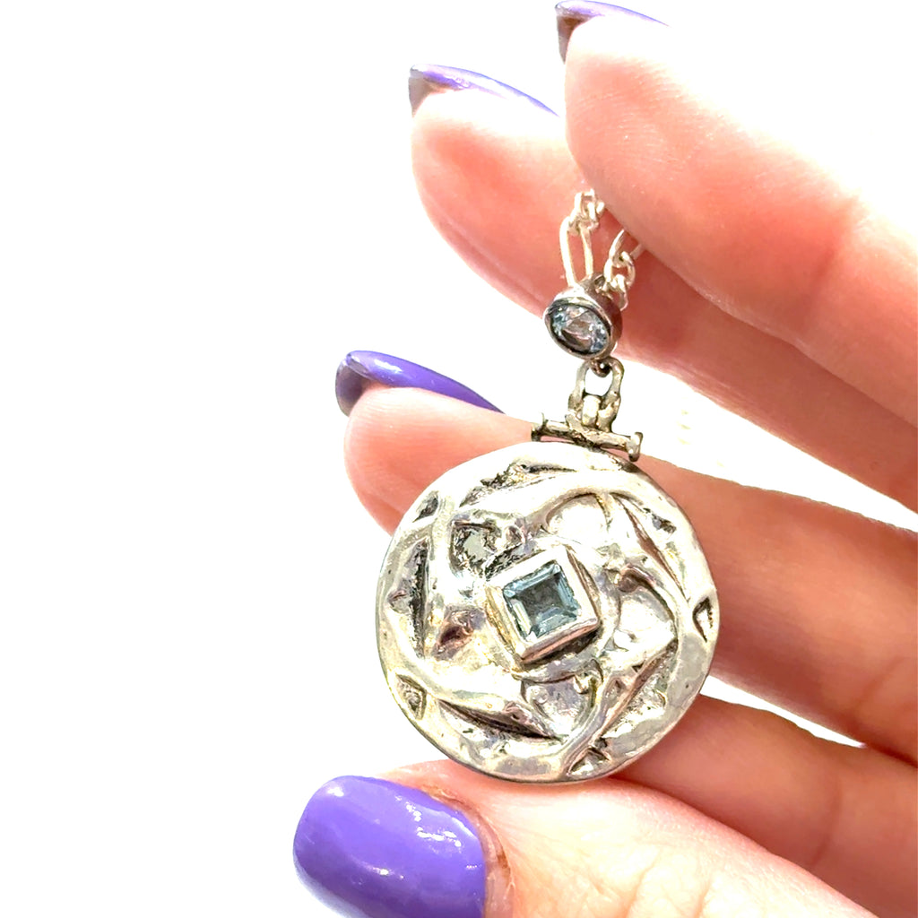Sterling Silver Blue Topaz Pendant Necklace on white center pendant in hand overview