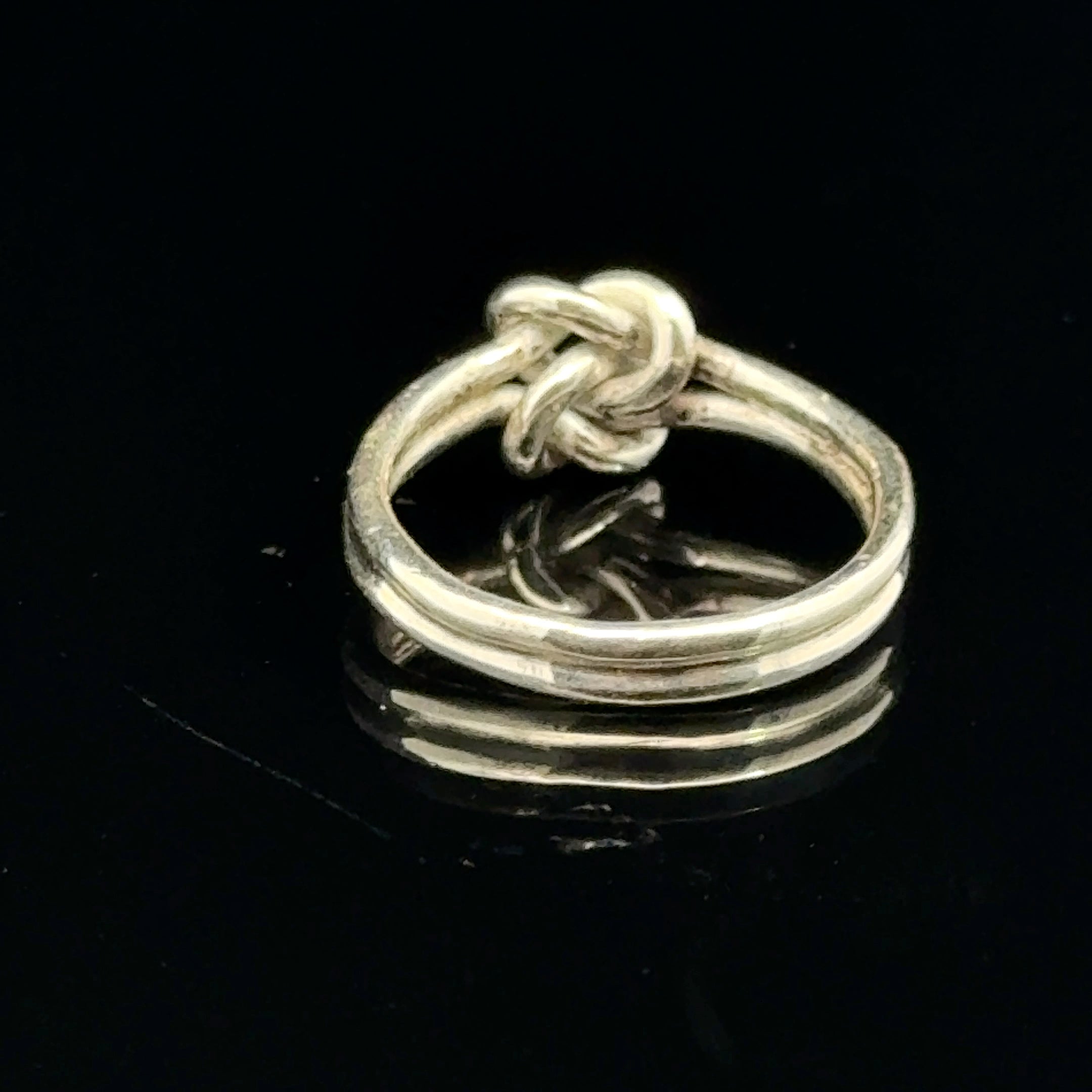 Sterling silver double knot ring handcrafted by Ivy Rose on a black background back side, close up overview. 