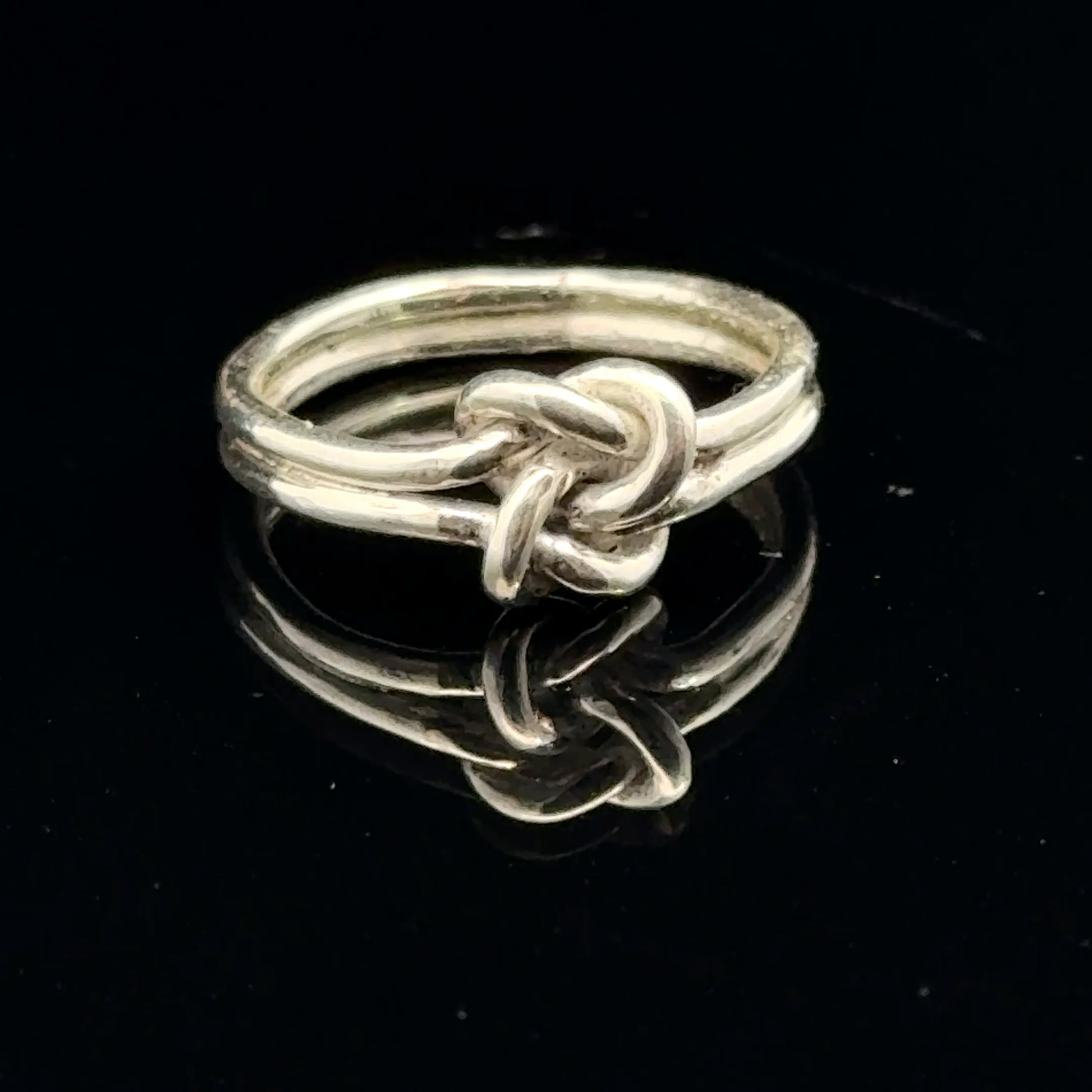 Sterling silver double knot ring handcrafted by Ivy Rose on a black background front overview. 