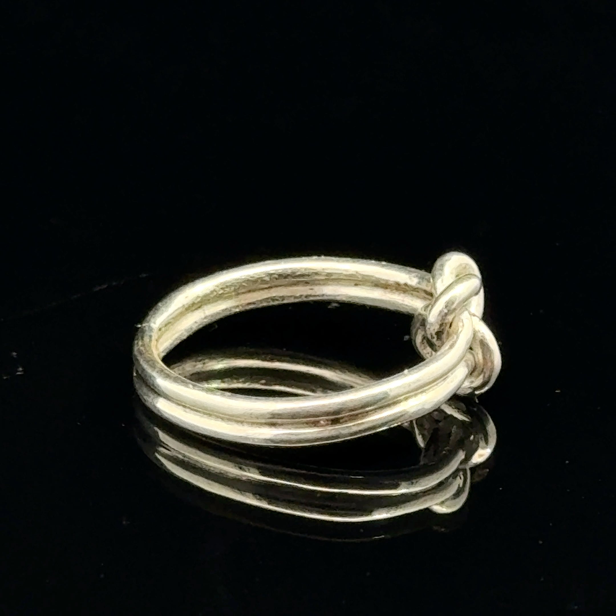 Sterling silver double knot ring handcrafted by Ivy Rose on a black background left side, close up overview. 
