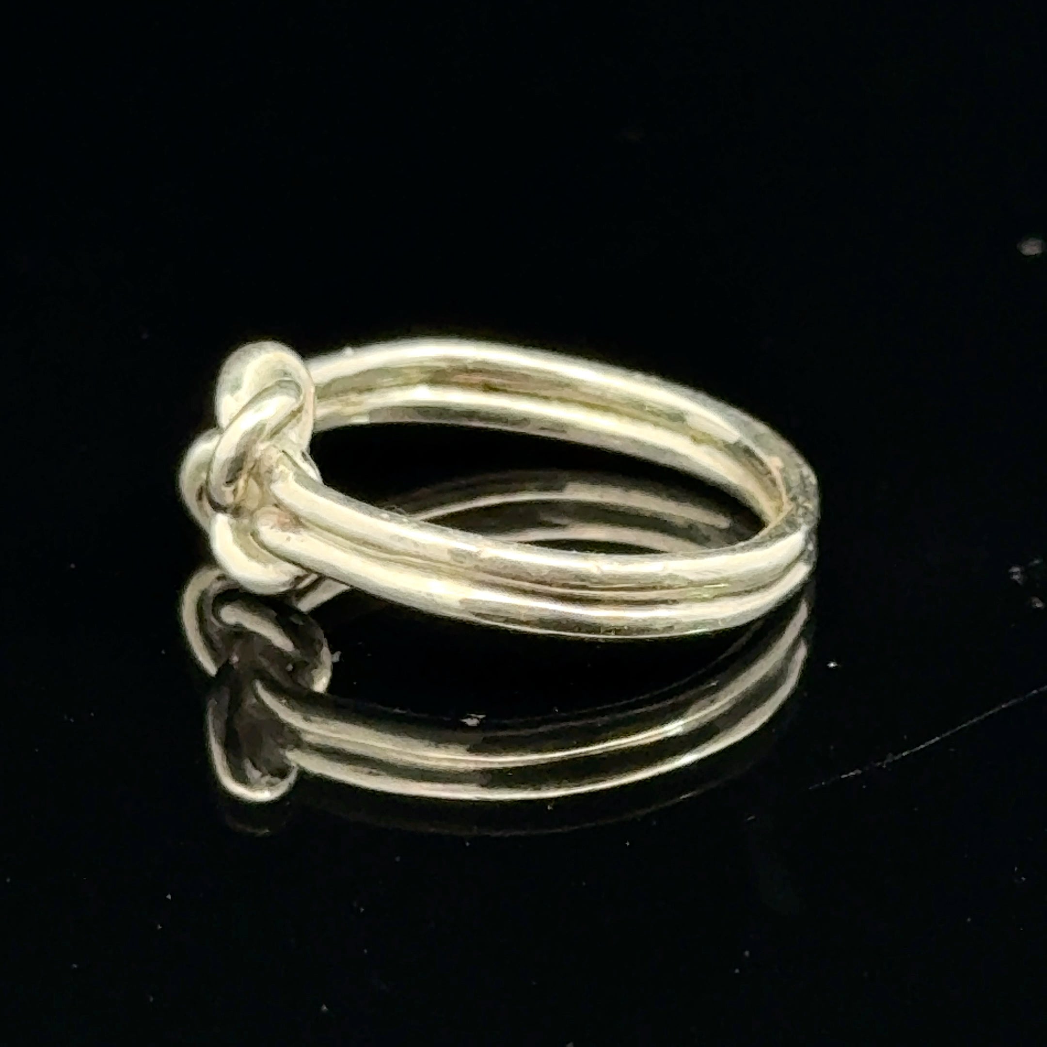 Sterling silver double knot ring handcrafted by Ivy Rose on a black background right side, close up overview. 