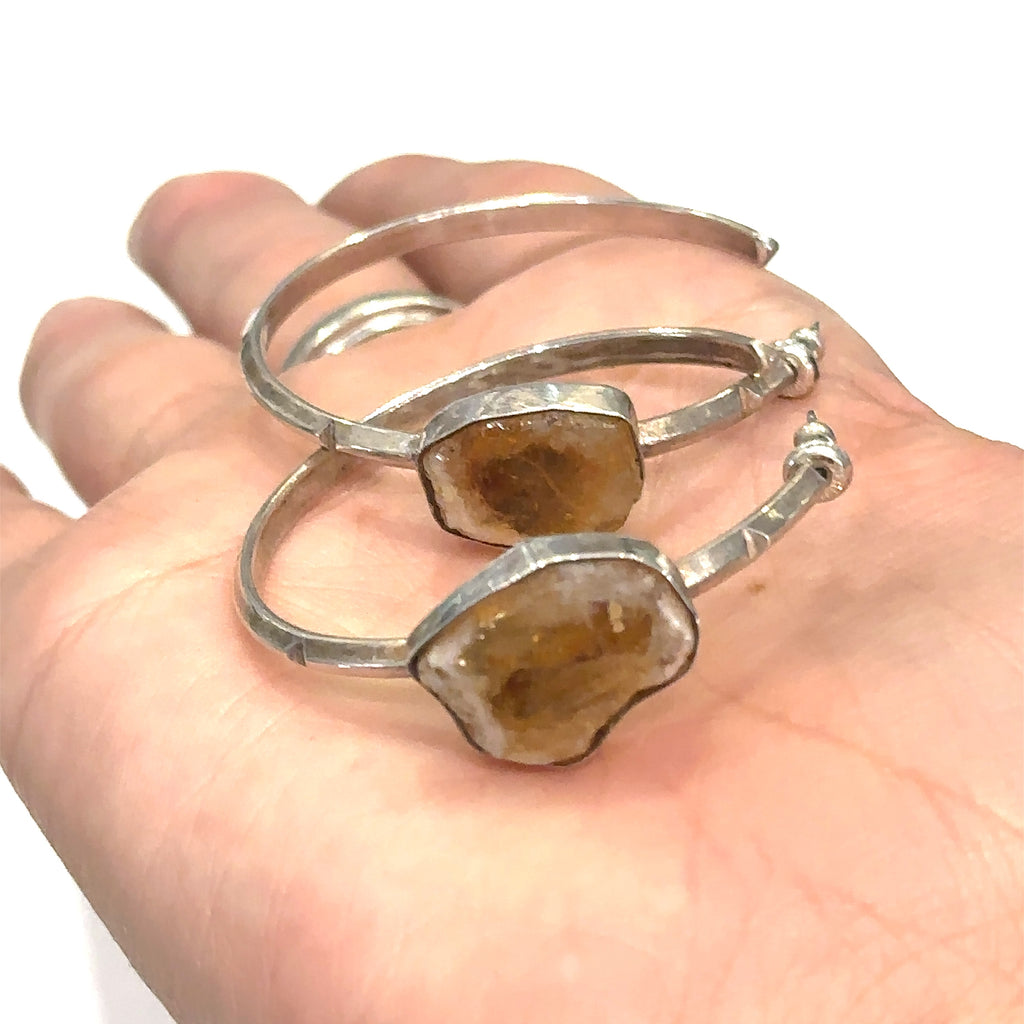 Sterling silver hoop stud earrings with raw citrine gemstones on white and in palm of hand for an overview