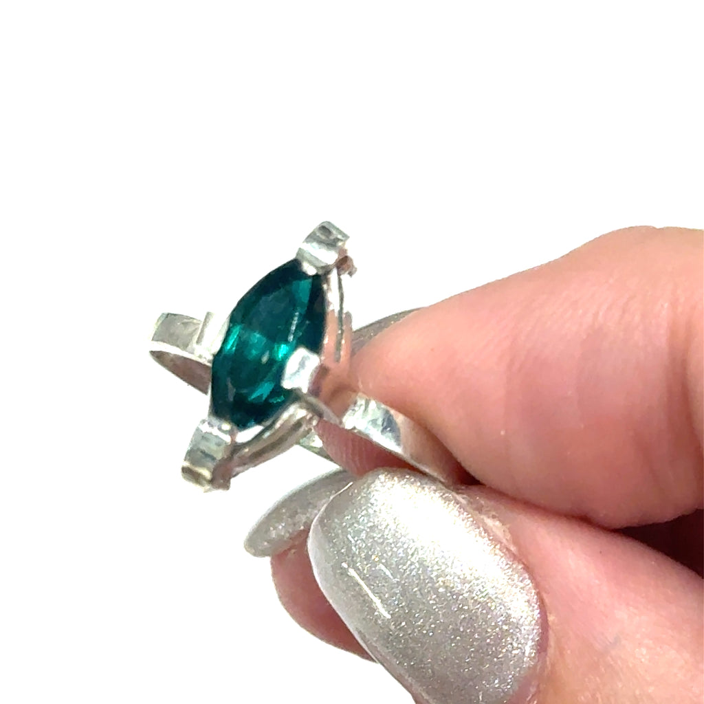 Sterling silver ring with faceted marquis emerald gemstone on a white background front, close up on a models finger tips view.