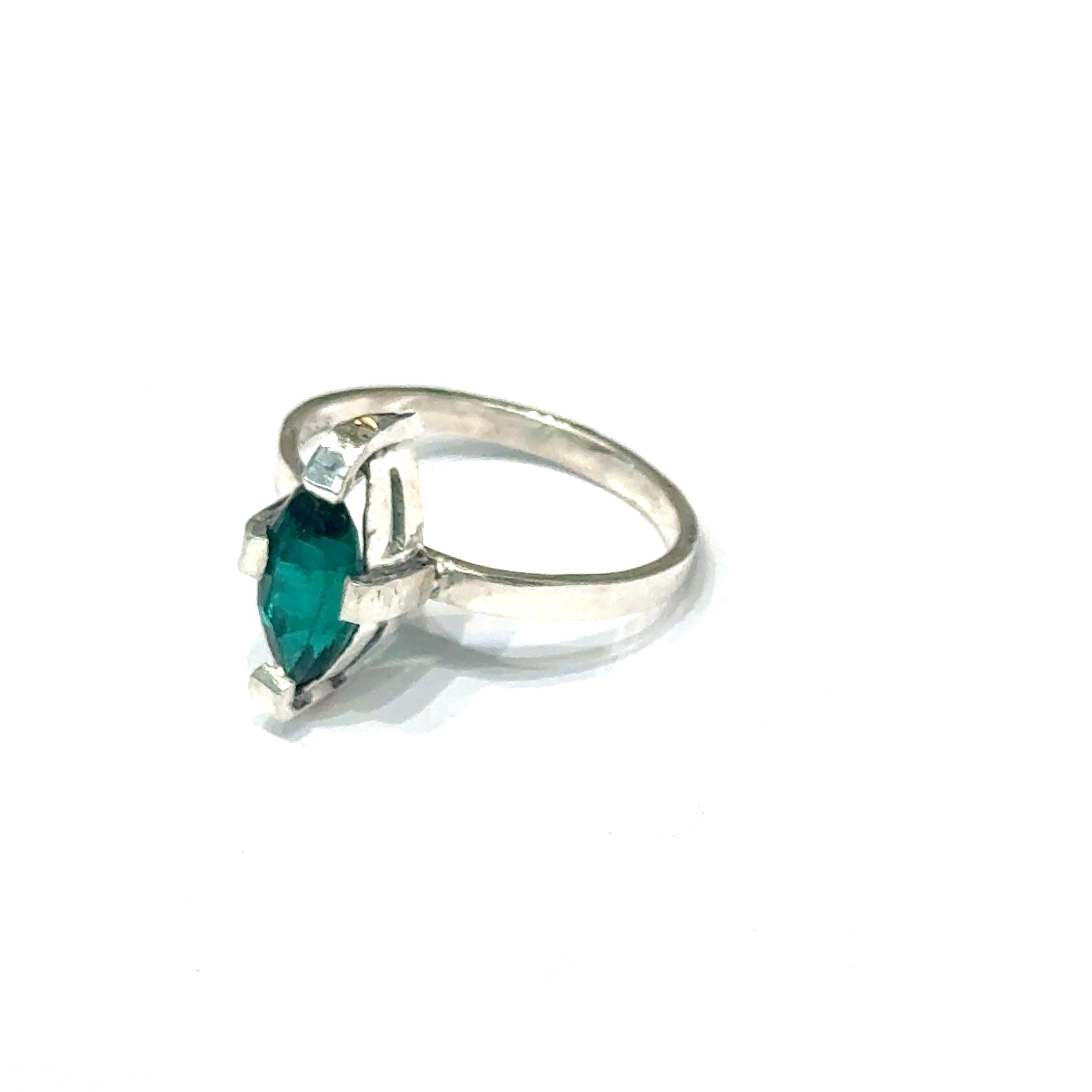 Sterling silver ring with faceted marquis emerald gemstone on a white background front, left angle close up  view.