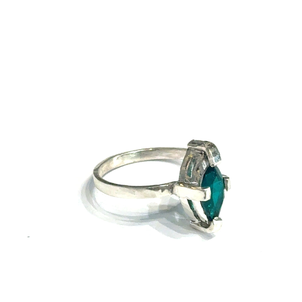 Sterling silver ring with faceted marquis emerald gemstone on a white background front right angle, close up  view.