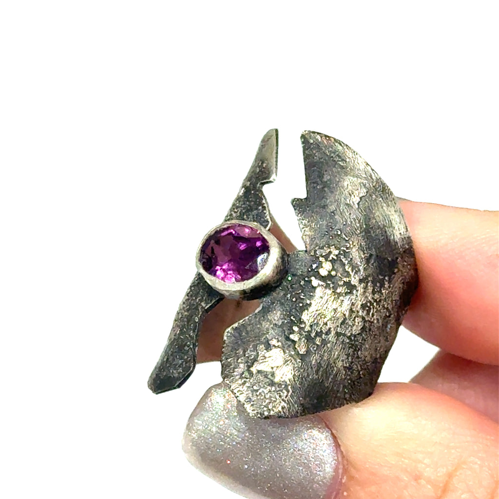 Sterling silver shield ring with almandine garnet center (size 6.5) on a white background, in models hand front, view. 