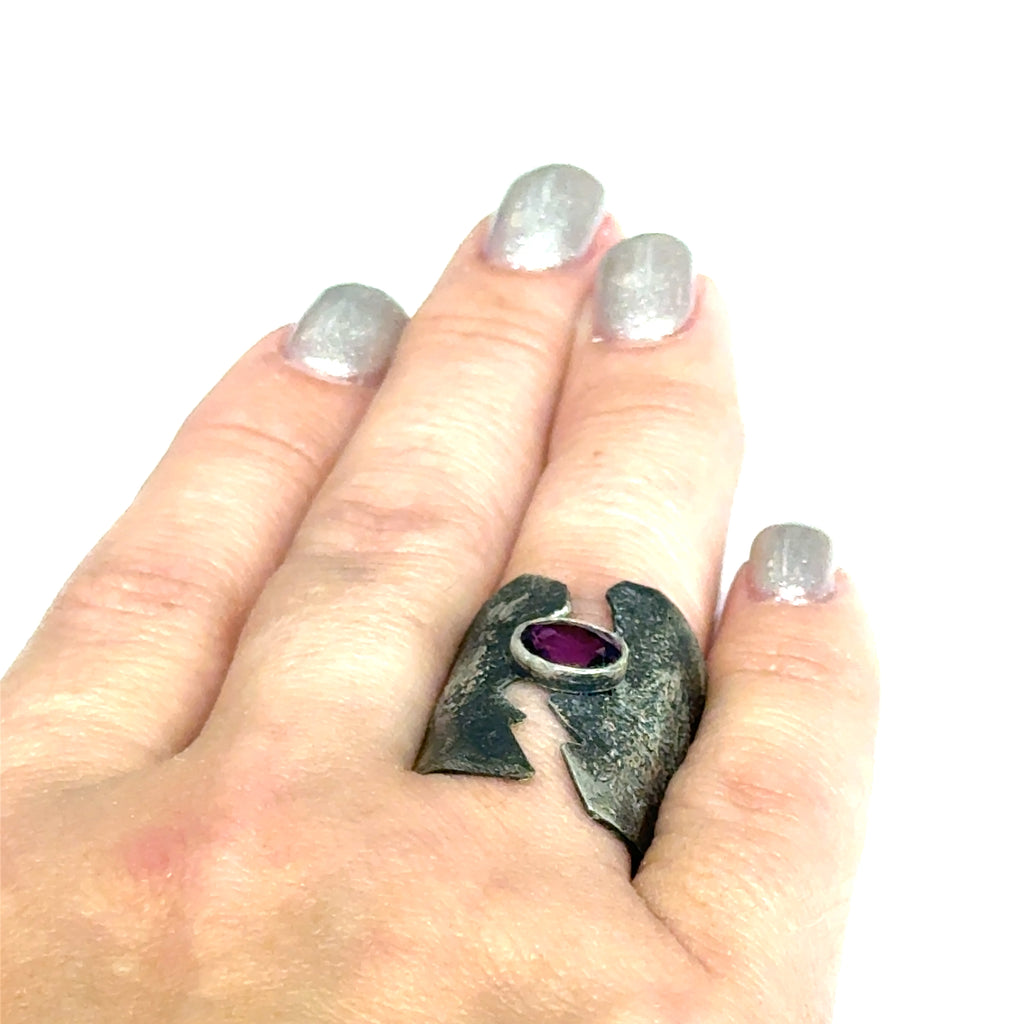Sterling silver shield ring with almandine garnet center (size 6.5) on a white background, on the  models finger front, overview. 