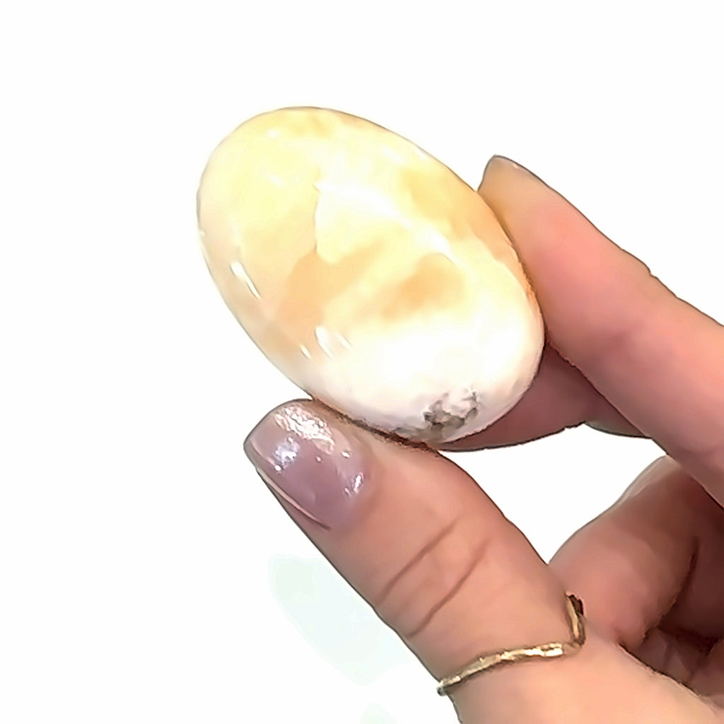 Stilbite Tumbled Gemstone on white in hand view