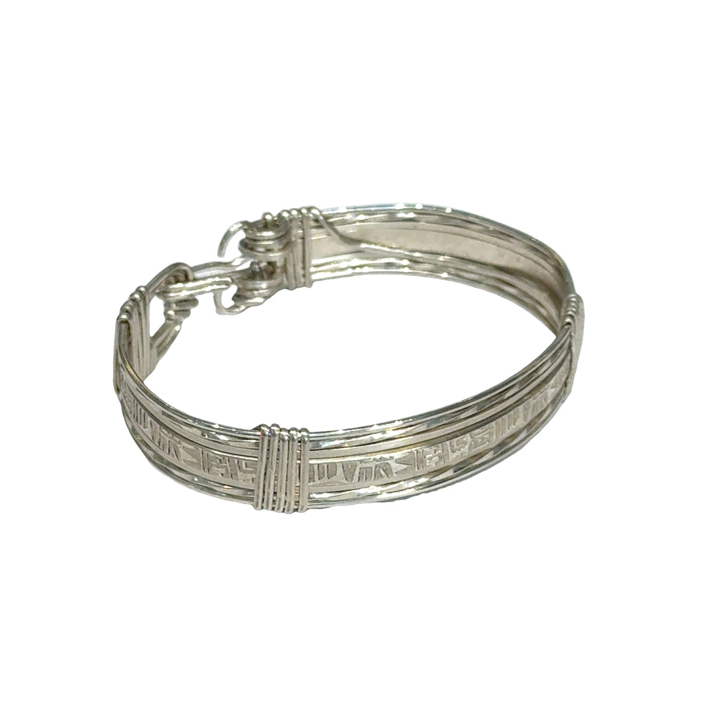 Style #3 Sterling silver bangle with twisted and straight wire featuring line-designed centerpiece showing elegant classic design, on a white background, front left angle close up view. 