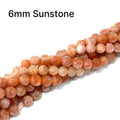 Sunstone 6mm smooth round gemstone strand on a white background, front overview. 