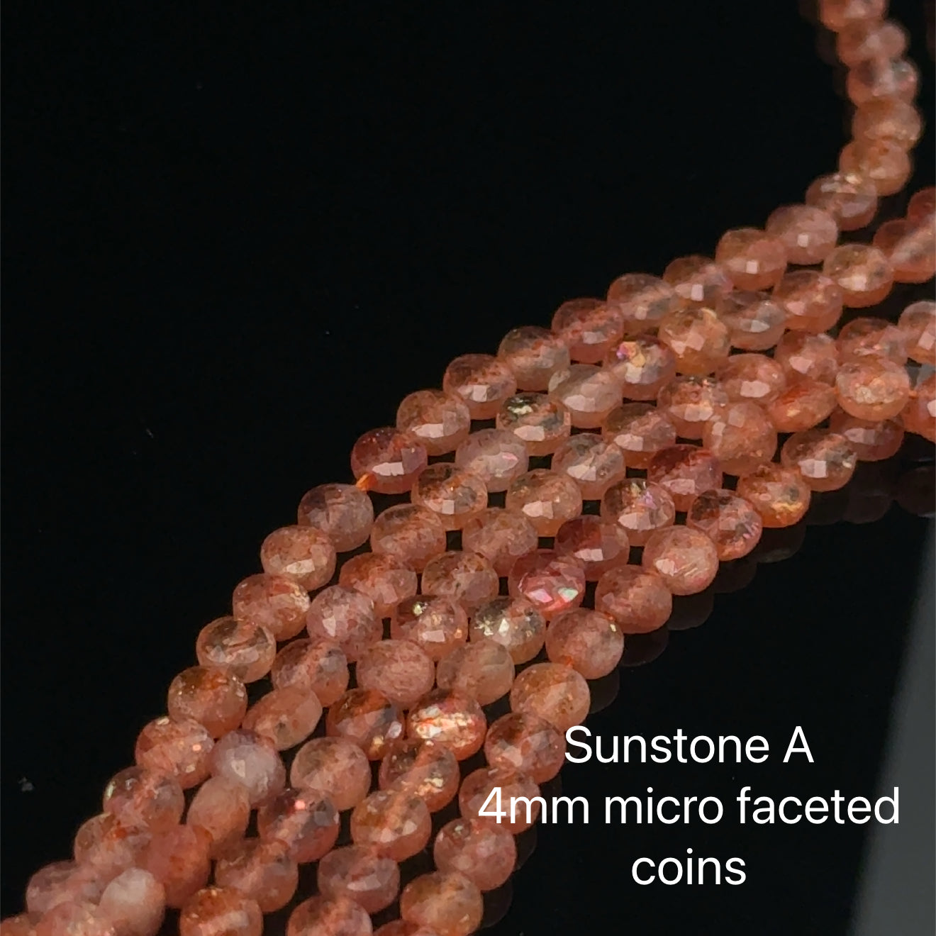 Sunstone: A 4mm micro faceted coin on a black background, front view. 