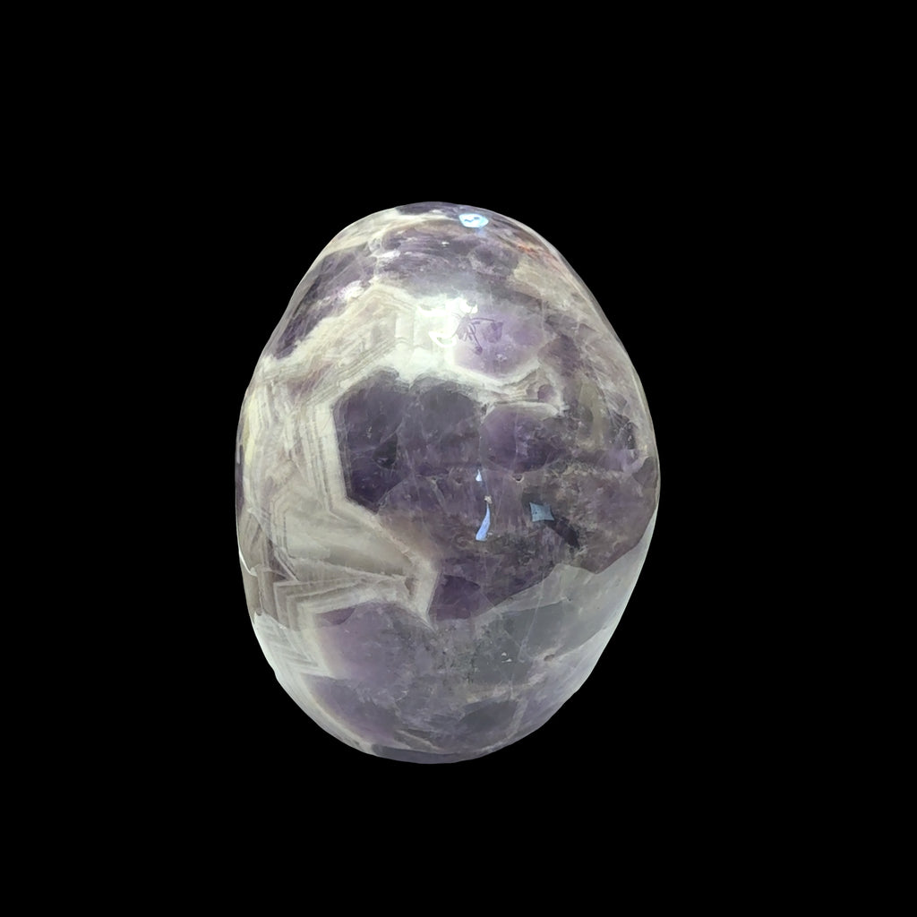 The largest of the two Trapiche Amethyst Gemstone carved skull on a black background,  back view. 