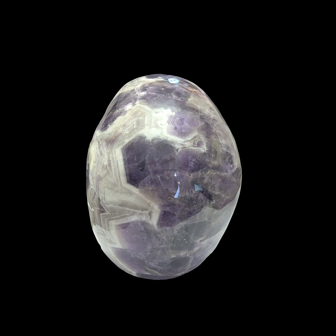 The largest of the two Trapiche Amethyst Gemstone carved skull on a black background,  back view. 
