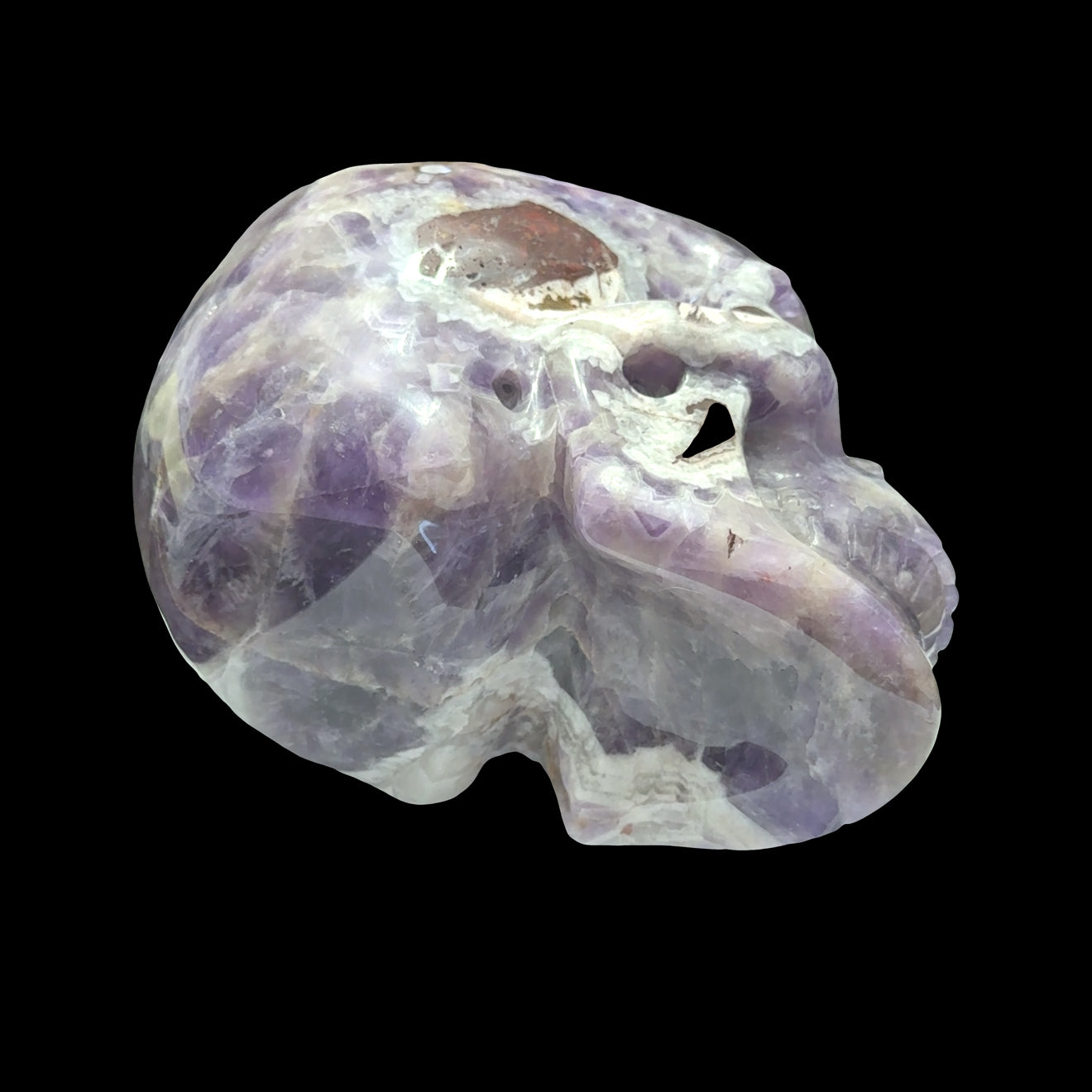The largest of the two Trapiche Amethyst Gemstone carved skull on a black background,  bottom view. 