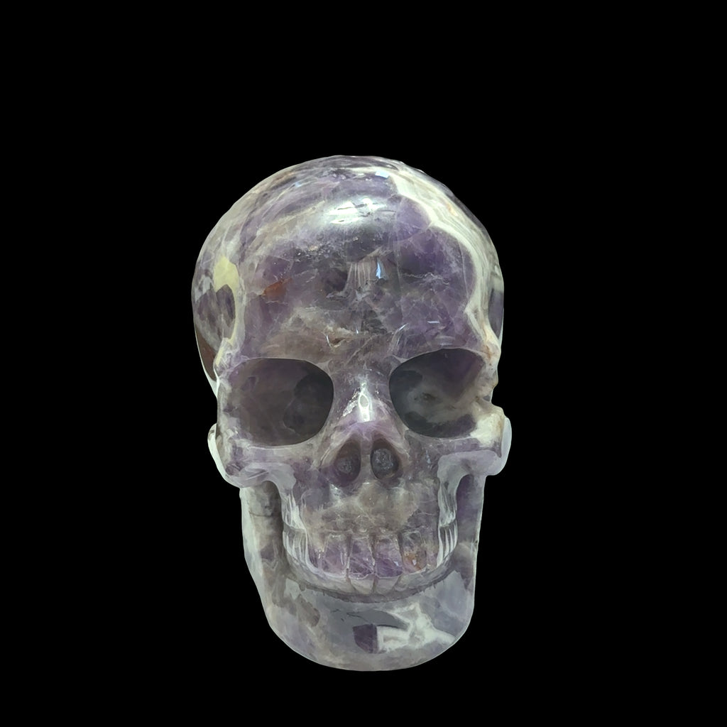 The largest of the two Trapiche Amethyst Gemstone carved skull on a black background,  front view. 